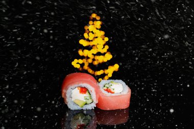 Suşi yeni yıla girer. Noel arkaplanı. Kartpostal, menü ve reklam için fikir. Işıklı bir köknar ağacının parladığı yerde, karanlık arka planda yuvarlan. Menü için dekorasyon