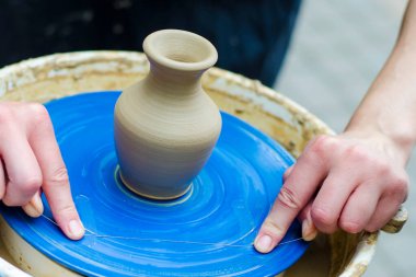Kil tenceresi ve onu yaratan eller. Çömlek atölyesinde ıslak kil ve el çömlekçisi tekerleği ile el yapımı vazo.