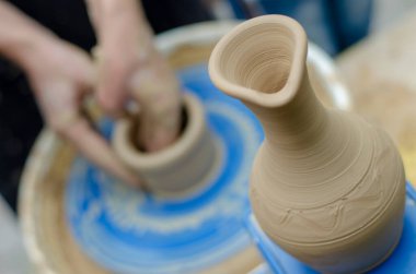 Kadın eli dönen çömlekçi çarkında hafif kille çalışır. Çömlek atölyesinde çömlekçi çarkında kil modellemesi üzerine sokak ustası sınıfı.