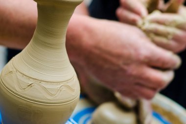 Çömlek atölyesindeki çömlekçi çarkında kil modellemesi üzerine sokak ustası sınıfı. Vazoya odaklan, vazoyu arka planda bulanıklaştırma işlemi