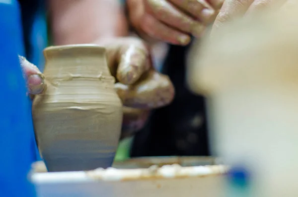 team work in a duet while studying an experienced master and student and providing clay forms. The process of changing the form from clay to the jug