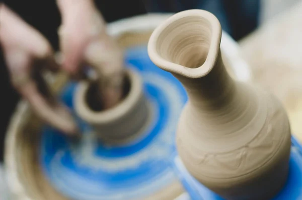 Street master class on modeling of clay on a potter\'s wheel In the pottery workshop. Focus on the vase, the process of making the vase blurred against the background