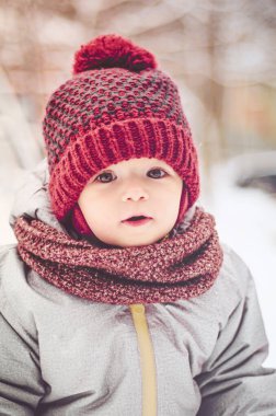 Mutlu gülümseyen çocuk güneşli kış gününde yürüyor, çocukların oyun bahçesinde karla oynuyor.