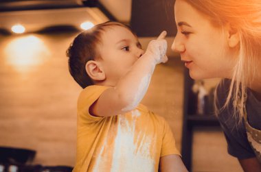 Mutfakta mutlu bir aile. Anne ve çocuk hamuru hazırlıyor, kurabiye pişiriyor. Mutfakta aile eğlencesi kavramı, çocuk çeşitli yemekler hazırlıyor: makarna, kurabiye, ekmek, zencefilli ekmek.. 