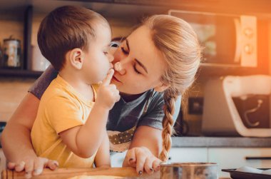 Mutfakta mutlu bir aile. Anne ve çocuk hamuru hazırlıyor, kurabiye pişiriyor. Mutfakta aile eğlencesi kavramı, çocuk çeşitli yemekler hazırlıyor: makarna, kurabiye, ekmek, zencefilli ekmek.. 