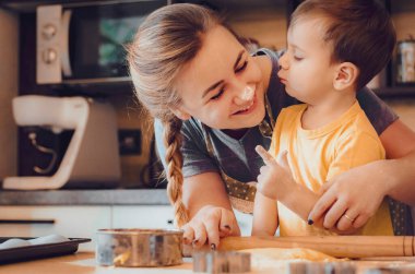 Mutlu aile anne ve çocuk mutfakta hamur yoğurur. Mutfakta aile eğlencesi kavramı, çocuk çeşitli yemekler hazırlıyor: makarna, kurabiye, ekmek, zencefilli ekmek.. 