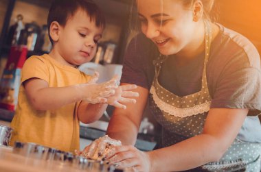 Mutfakta mutlu bir aile. Anne ve çocuk hamuru hazırlıyor, kurabiye pişiriyor. Mutfakta aile eğlencesi kavramı, çocuk çeşitli yemekler hazırlıyor: makarna, kurabiye, ekmek, zencefilli ekmek.. 