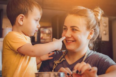 Mutfakta mutlu bir aile. Anne ve çocuk hamuru hazırlıyor, kurabiye pişiriyor. Mutfakta aile eğlencesi kavramı, çocuk çeşitli yemekler hazırlıyor: makarna, kurabiye, ekmek, zencefilli ekmek.. 
