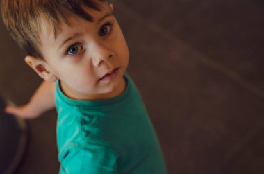 Yeşil tişörtlü bebek annesine bakıyor. Aşağıdan yukarıya bir bakış. Yukarıdan bir fotoğraf. Aile ilişkileri kavramı