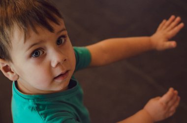 Yeşil tişörtlü bebek annesine bakıyor. Aşağıdan yukarıya bir bakış. Yukarıdan bir fotoğraf. Aile ilişkileri kavramı
