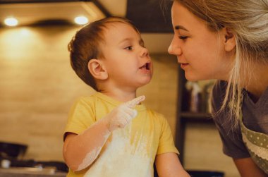 Mutlu aile birlikte fırın hazırlıyor. Anne ve çocuk çocuk kurabiye pişiriyor ve mutfakta eğleniyorlar. Ev yapımı yemek ve küçük bir yardımcı..