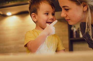 Mutfakta mutlu bir aile. Anne ve çocuk hamuru hazırlıyor, kurabiye pişiriyor. Mutfakta aile eğlencesi kavramı, çocuk çeşitli yemekler hazırlıyor: makarna, kurabiye, ekmek, zencefilli ekmek.. 