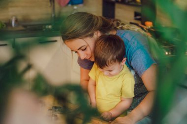Mutfakta mutlu bir aile. Anne ve çocuk hamuru hazırlıyor, kurabiye pişiriyor. Mutfakta aile eğlencesi kavramı, çocuk çeşitli yemekler hazırlıyor: makarna, kurabiye, ekmek, zencefilli ekmek.. 