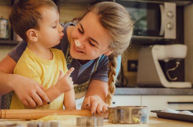 Mutlu aile anne ve çocuk mutfakta hamur yoğurur. Mutfakta aile eğlencesi kavramı, çocuk çeşitli yemekler hazırlıyor: makarna, kurabiye, ekmek, zencefilli ekmek.. 