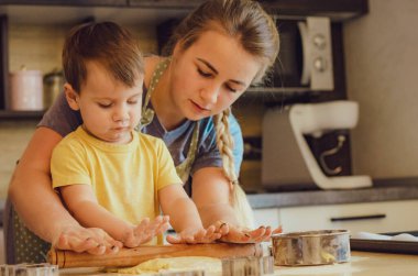 Mutlu aile anne ve çocuk mutfakta hamur yoğurur. Mutfakta aile eğlencesi kavramı, çocuk çeşitli yemekler hazırlıyor: makarna, kurabiye, ekmek, zencefilli ekmek.. 