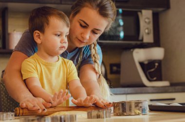 Mutfakta mutlu bir aile. Anne ve çocuk hamuru hazırlıyor, kurabiye pişiriyor. Mutfakta aile eğlencesi kavramı, çocuk çeşitli yemekler hazırlıyor: makarna, kurabiye, ekmek, zencefilli ekmek.. 