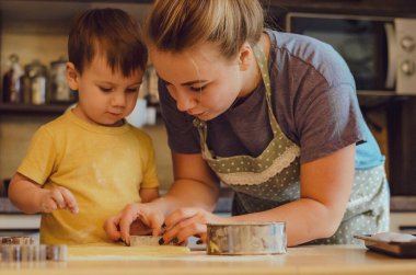 Mutlu aile anne ve çocuk mutfakta hamur yoğurur. Mutfakta aile eğlencesi kavramı, çocuk çeşitli yemekler hazırlıyor: makarna, kurabiye, ekmek, zencefilli ekmek.. 