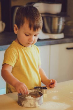Büyük gözlü, çekici görünümlü sarı tişörtlü güzel bir çocuk. Gülümsüyor, odasında ve mutfakta hediyeler veriyor.