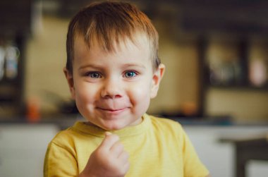 Mutlu çocuk portresi. Odasına ya da mutfağa yakın gülümsüyor.
