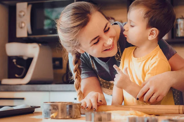 Mutlu aile anne ve çocuk mutfakta hamur yoğurur. Mutfakta aile eğlencesi kavramı, çocuk çeşitli yemekler hazırlıyor: makarna, kurabiye, ekmek, zencefilli ekmek.. 