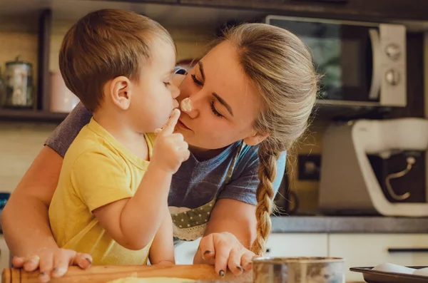 Mutfakta mutlu bir aile. Anne ve çocuk hamuru hazırlıyor, kurabiye pişiriyor. Mutfakta aile eğlencesi kavramı, çocuk çeşitli yemekler hazırlıyor: makarna, kurabiye, ekmek, zencefilli ekmek.. 