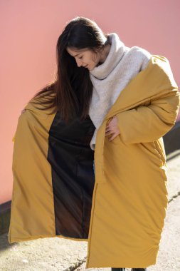 Parlak sarı kabarık ceketli güzel bir kızın fotoğraf çekimi ya da şık kışlık kadın kıyafetlerinin sergilendiği bir gösteri için sokaktaki palto.