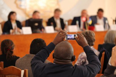21.01.2018 Vinnitsa, Ukrayna: Afro-Amerikalı bir adam, milletvekilleri ve memurların bir hükümet toplantısında oturdukları bir kürsünün fotoğraflarını çekiyor