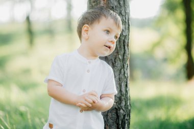 Dışarıda oynayan, mavi gözlü, beyaz gömlekli şık sarışın çocuk.