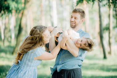 Mutlu ebeveynler kollarında bebekle oynarlar. Babasının annesi ve küçük oğlu kollarında, aile tatili için Natur 'a gittiler.