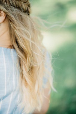 Mavi elbiseli güzel sarışın bir kadın güneşli bir havada parkta yürür. Güzel bir kız gülümsüyor.