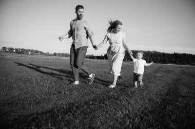 Oğlu babasını tarlada yakalar, babası koşar ve bakar. Mutlu aile kavramı, ebeveynlik, aile istirahatı, doğada birlikte zaman geçirmek.