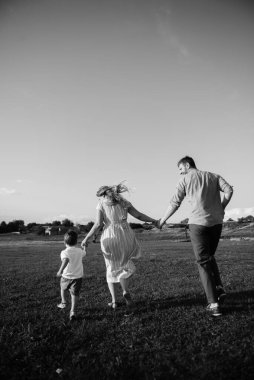 Oğlu babasını tarlada yakalar, babası koşar ve bakar. Mutlu aile kavramı, ebeveynlik, aile istirahatı, doğada birlikte zaman geçirmek.