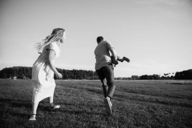 Küçük çocuk babasının omuzlarında oturuyor ve mutlu bir günde tarlada güneşi işaret ediyor.