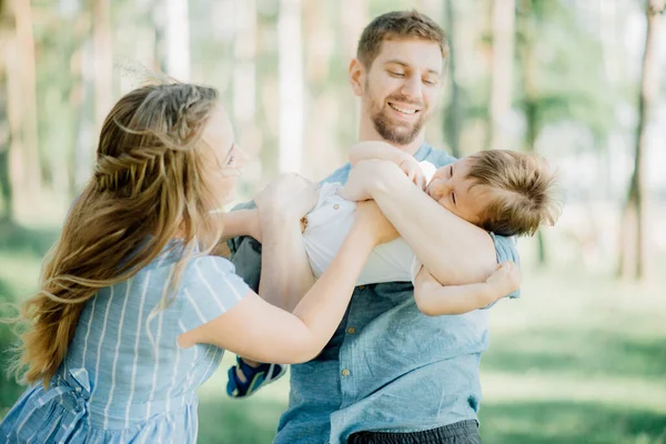 幸せな親は赤ん坊と腕で遊ぶ 父親の母親と彼らの小さな息子は彼らの腕の中で 自然家族の休暇 — ストック写真