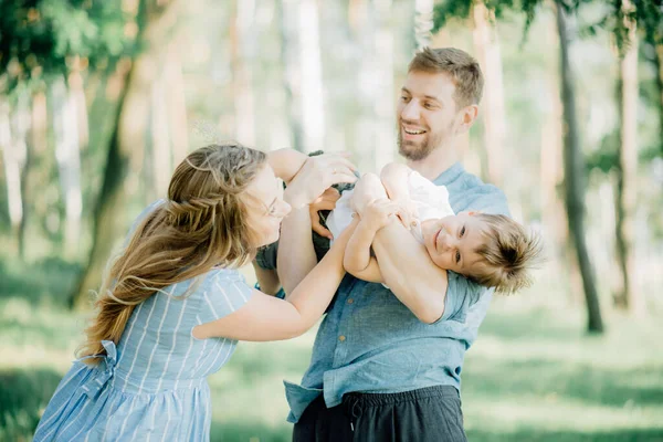 快乐的父母抱着孩子玩耍 父亲的母亲和他们的小儿子都在他们的怀里 一家人都在大自然里度假 — 图库照片