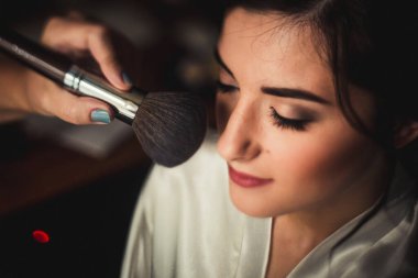 Makyözün gelinlik makyajı için taşa dokunduğu güzel bir kızın yüzü.