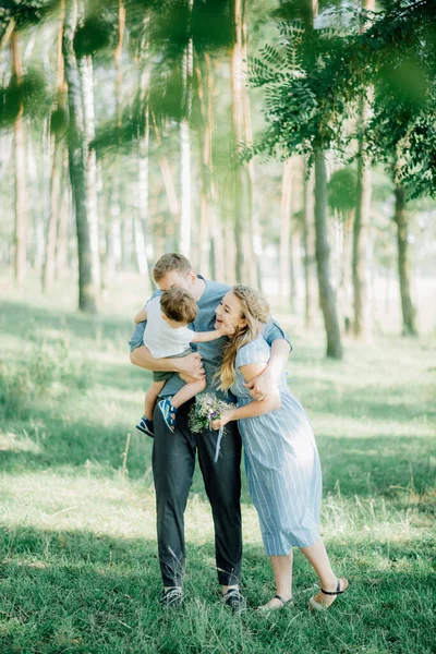 幸せな若い家族は緑の自然の中で一緒に時間を過ごす — ストック写真