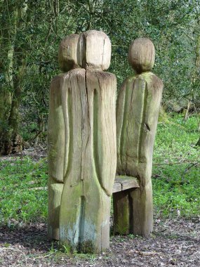 Orman yürüyüşündeki bankın etrafında oyulmuş figürler.