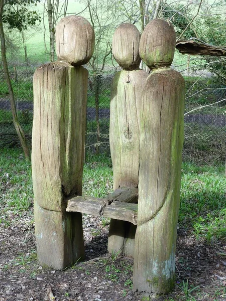 木立の上にベンチを囲む彫刻された人物 — ストック写真