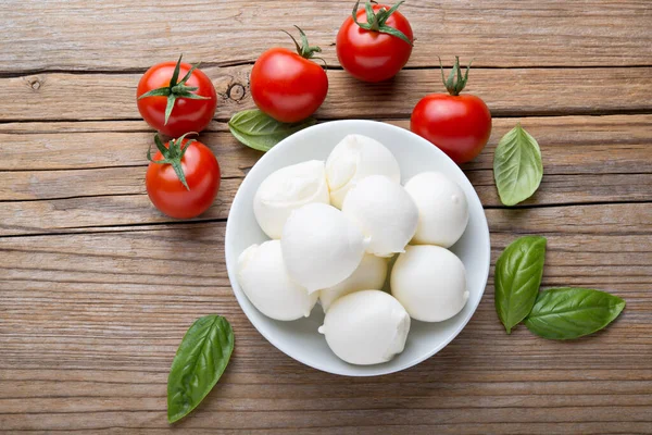 Küçük mozzarella topları, kiraz domatesleri ve fesleğen. Üst görünüm.