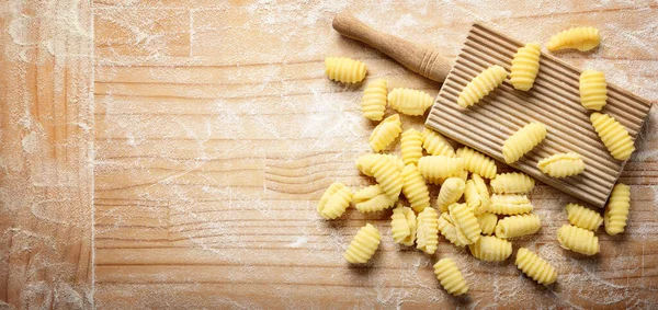 Durum buğdaylı irmik gnocchi ve hamur işi tahtasında gnocchi. İçindekiler: statebuğday irmiği, su, tuz. Üst görünüm, metin için boşluk. 