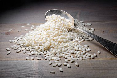 Çiğ Arborio Rice ve ahşap arka planda eski bir kaşık.