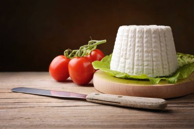 Ricotta cheese and tomatoes on old wooden table. clipart