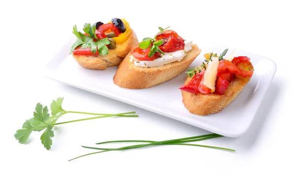 Ekmek, biber, kiraz domates, peynir, zeytin, kapari ve beyaz arka planda izole edilmiş aromatik otlarla küçük kırmızı aperatifler..