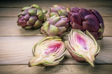Small artichokes on old wooden table.  clipart