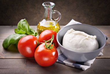 Mozzarella, domates, fesleğen ve ahşap masada ekstra saf zeytinyağı..