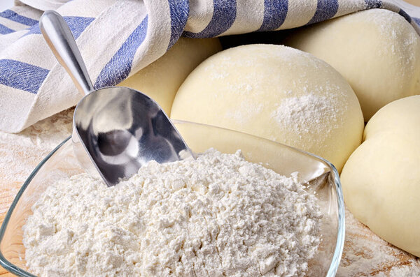 Leavened pizza dough with flour and scoop.