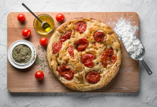 Bari tarzı Focaccia ekmeği. Kiraz domatesli Focaccia Barese, beyaz alçı arka planda zeytinyağı ve kekik otu, üst manzara.