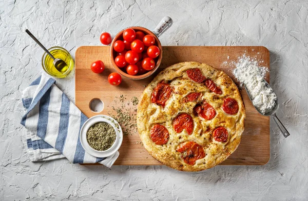 Bari tarzı Focaccia ekmeği. Kiraz domatesli Focaccia Barese, beyaz alçı arka planda zeytinyağı ve kekik otu, üst manzara.