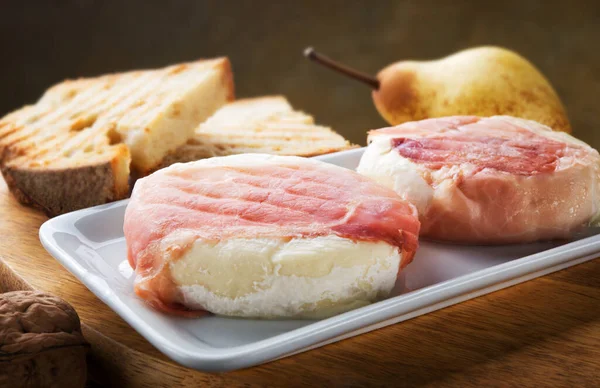 Noktalı ızgara tomino peyniri (tomino boscaiolo) tipik İtalyan Piedmontese peyniri, ekmek, ceviz ve armut, yakın plan, seçici odaklanma.